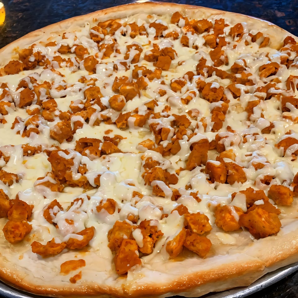 Via Roma Pizza's buffalo chicken pizza, topped with melted mozzarella and white sauce drizzle.