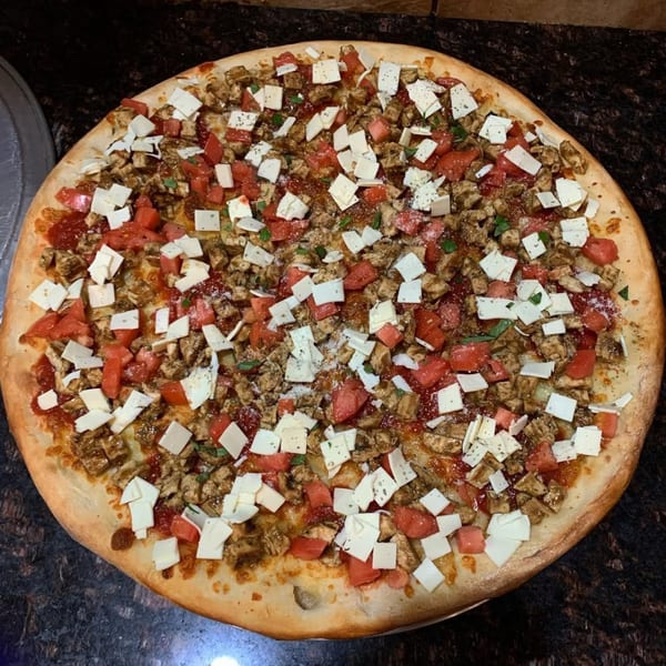 Via Roma Pizza's chicken, tomato, and cheese pizza, topped with herbs and spices.