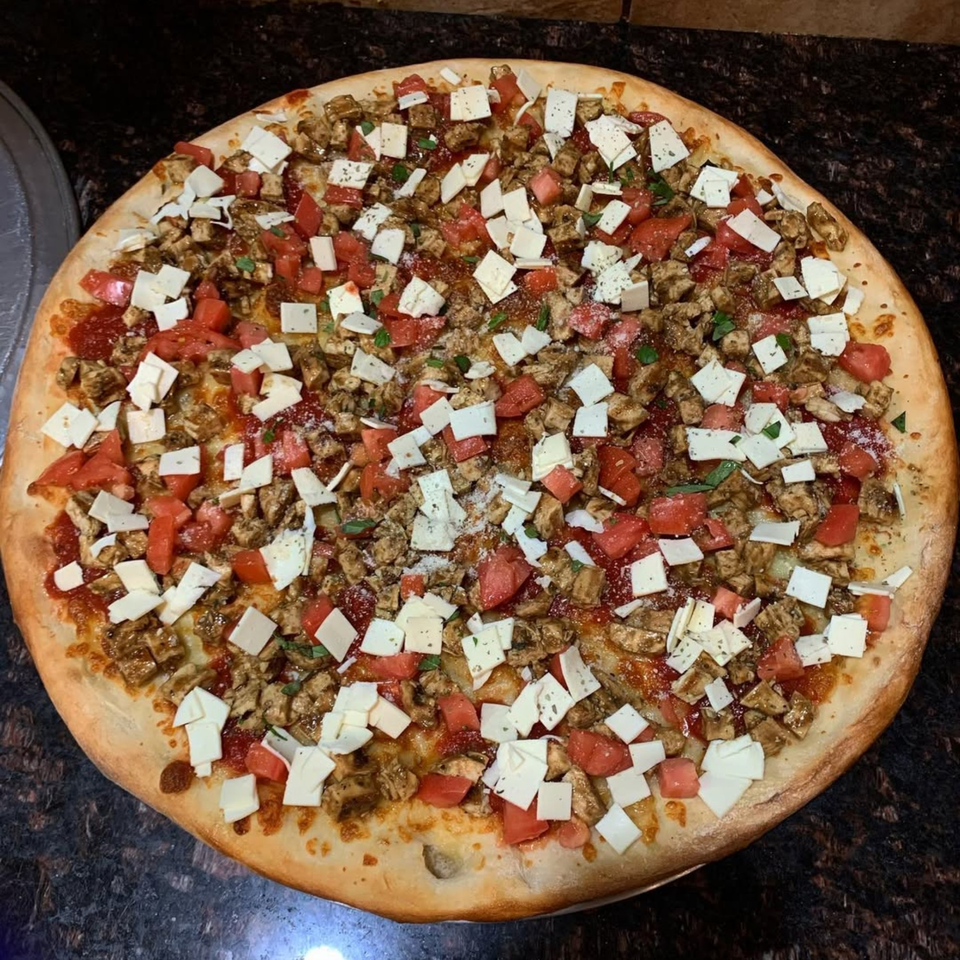 Via Roma Pizza's chicken, tomato, and cheese pizza, topped with herbs and spices.